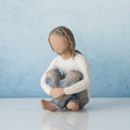 Faceless young girl figurine wearing white shirt and blue jeans sitting with her hands on her knees