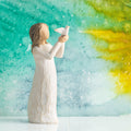 Willow Tree Soar, 5”h hand-painted standing figure in cream dress holding white dove in outstretched hands, in front of teal painting