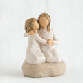 Two blonde faceless girls wearing white dresses hugging another on rock figurine