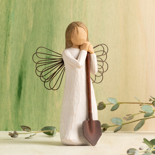 Willow Tree Angel of the Garden, 5.5”h hand-painted standing resin figure in cream dress with wire wings, leaning against brown metal shovel, in front of green painting