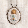 Oval bas-relief carving of figure holding sprig of rosemary, edged in pierced-metal filigree with brown elastic ornament loop
