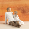Willow Tree Father and Daughter, 5”h hand-painted resin figure of seated man dressed in neutral colors, legs outstretched, daughter in cream dress by his side, in front of sienna painting