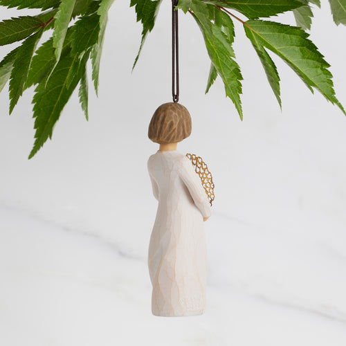 Back view: Dated Ornament of figure holding pierced gold-leaf wreath of hearts. 2024 written on wreath; loop and hook in head