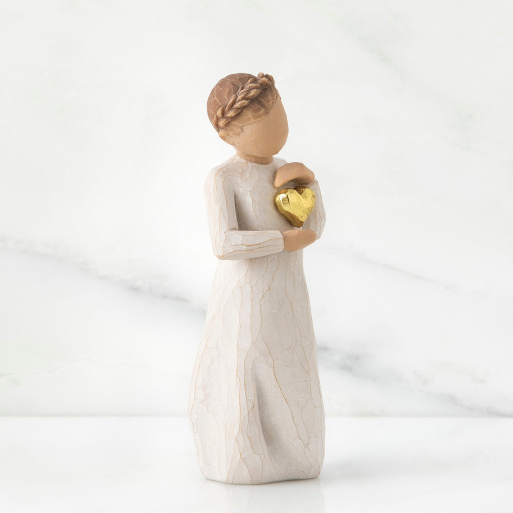 Brunette girl figurine in white dress holding gold heart
