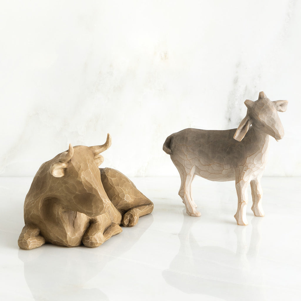 Golden cow figurine next to grey sheep figurine