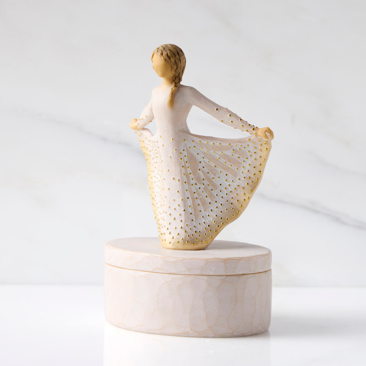 Left view: oval resin box, with 3-D figure atop lid, in cream and gold carved dress