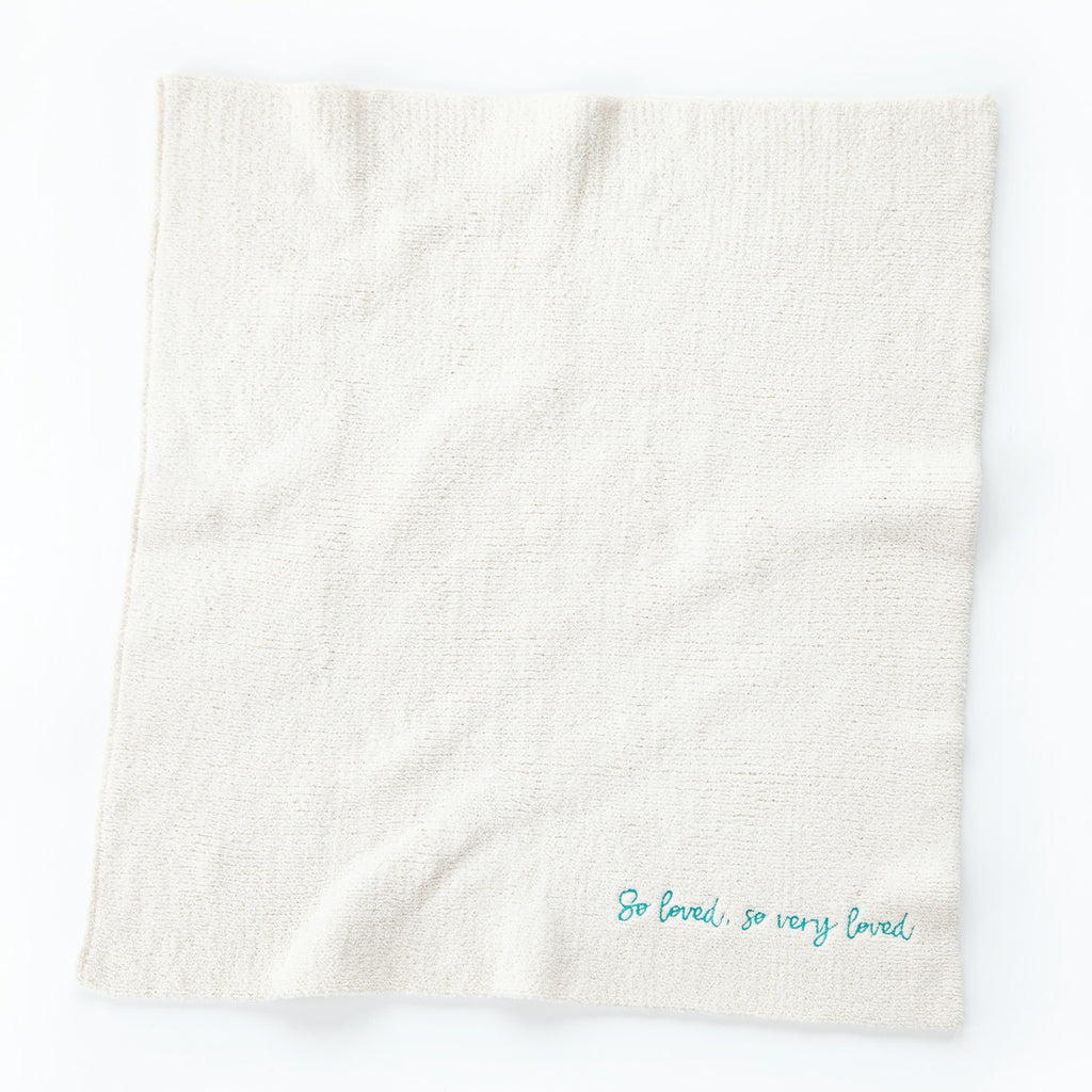 Overview of white towel with 'so loved, so very loved' in light blue in the right corner
