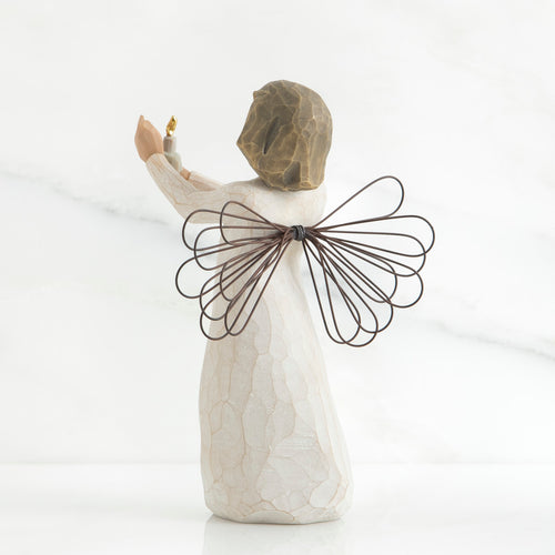 Back view of brunette girl figurine in white dress with brown wire wings holding up candle