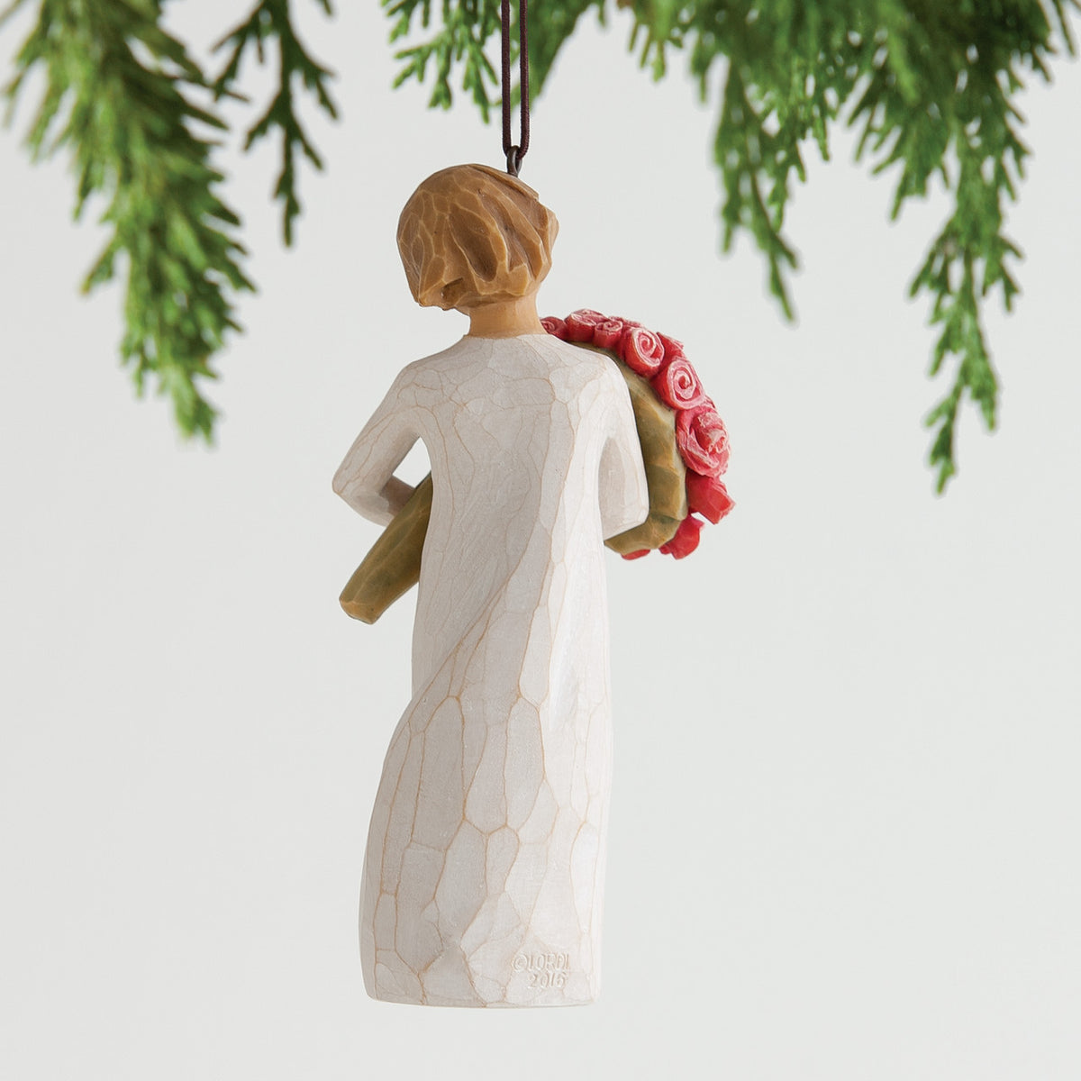 Back view of brunette woman figurine wearing white dress holding pink flowers hanging from tree