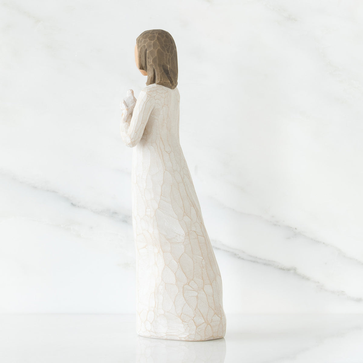 Brunette girl figurine in white dress facing away from camera