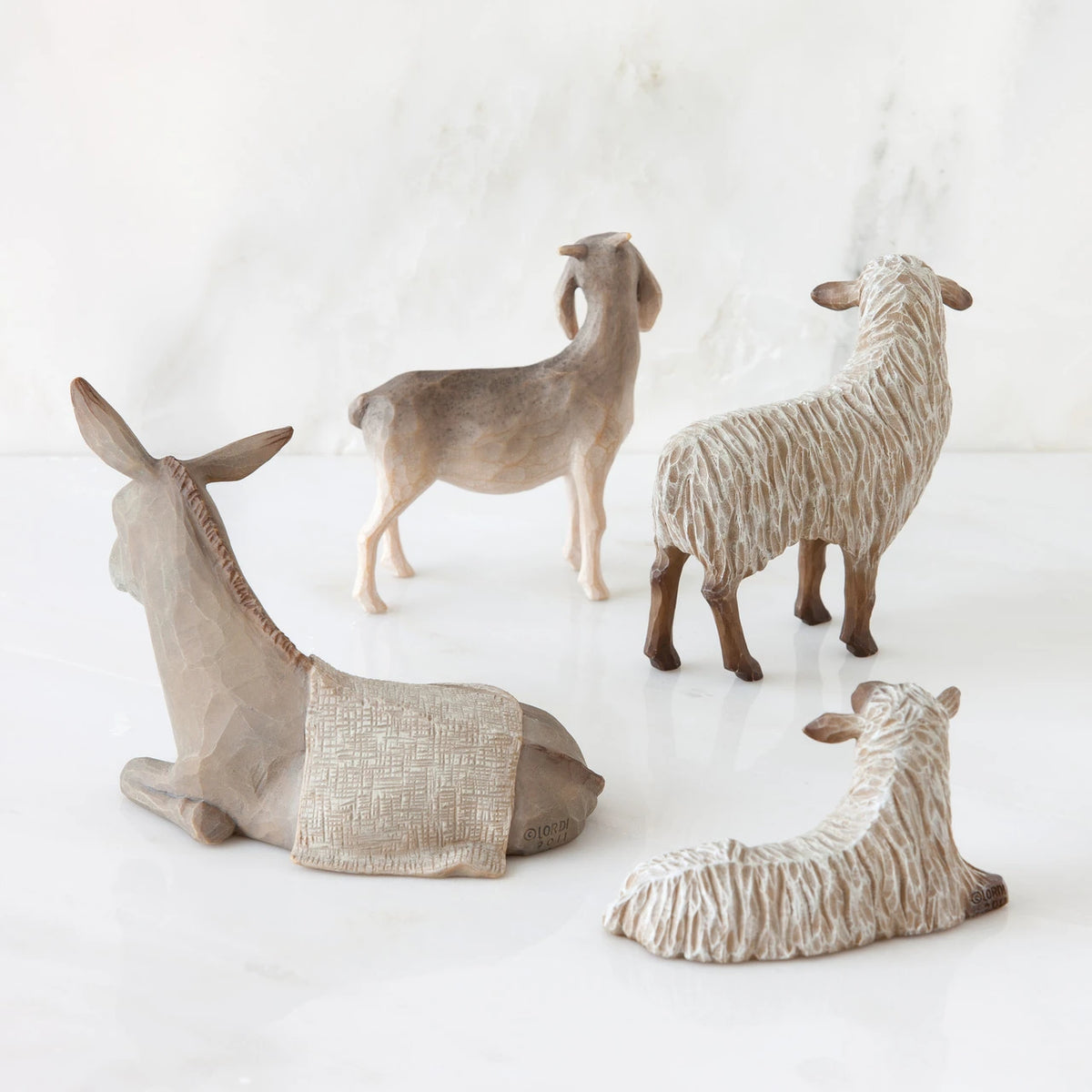 Set of two white sheep figurines next to donkey and goat figurine