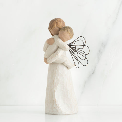 Angel figurine with black wire wings  in white holding baby in her arms
