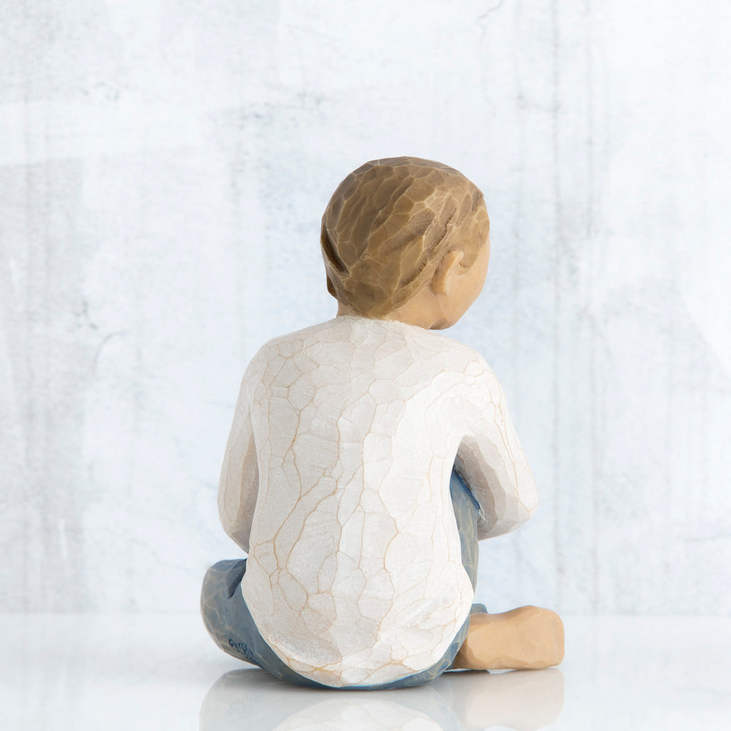 Back view of boy figurine sitting wearing white shirt