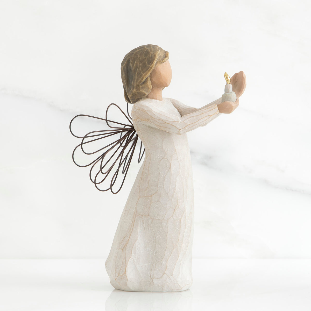 Side view of brunette girl figurine in white dress with brown wire wings holding up candle
