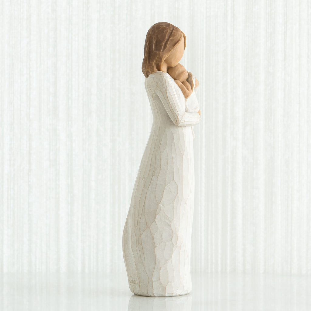 Side view of brunette woman figurine in white dress holding baby