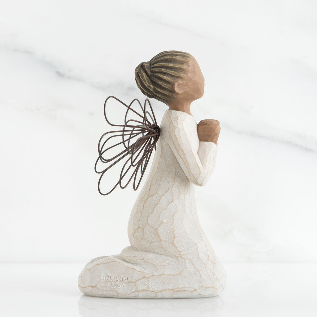 Side view of brunette angel figurine in white dress kneeling holding hands in prayer