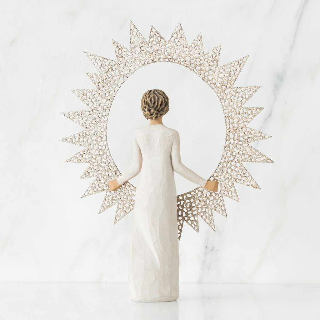 Back view of brunette girl figurine in white dress holding sun figurine up