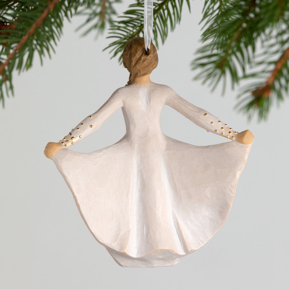 Back view, figure in cream dress, holds skirt with both hands, carved like monarch, dotted with gold. Hook, loop on ornament's head