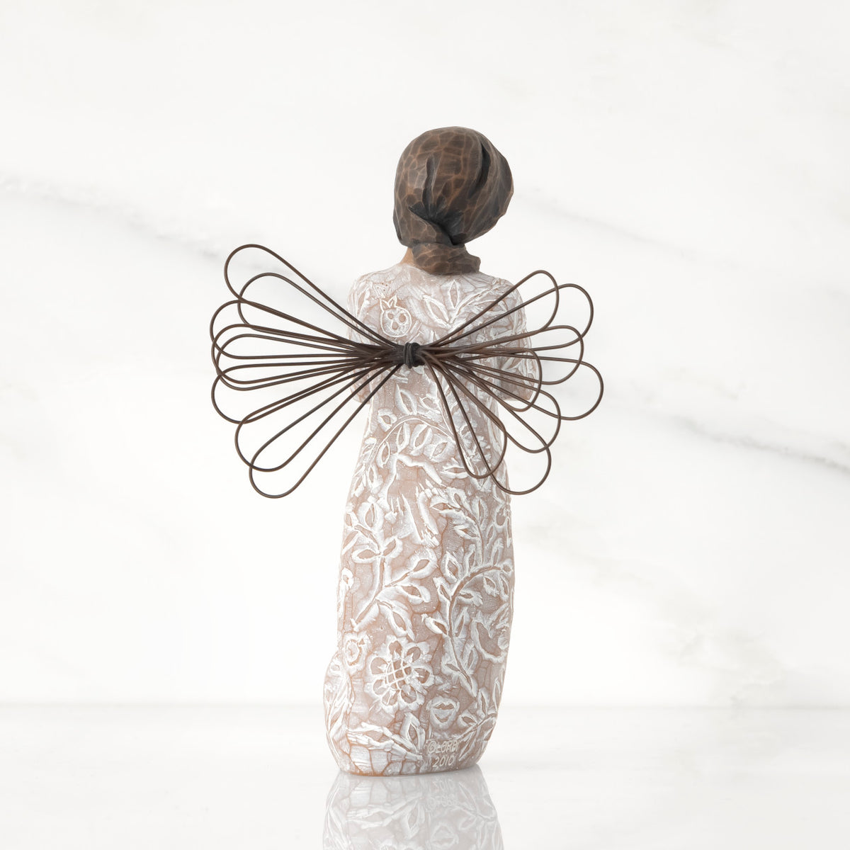 Back view: angel with wire wings, darker skin, dress carved with symbols of remembrance