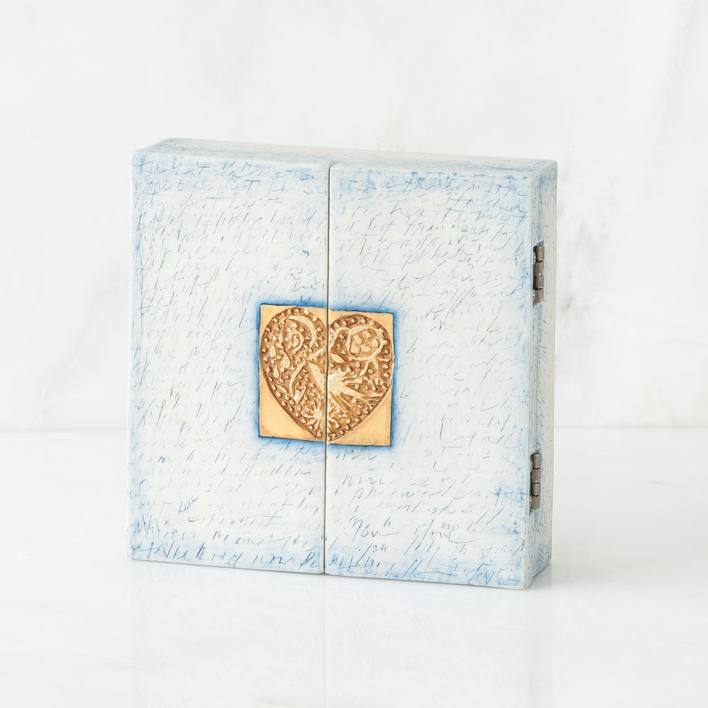 White/blue box with gold heart pendant centered