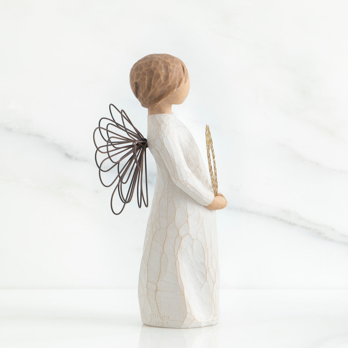 Left side view of angel with short, light brown hair holding a metallic wreath of hearts with both hands