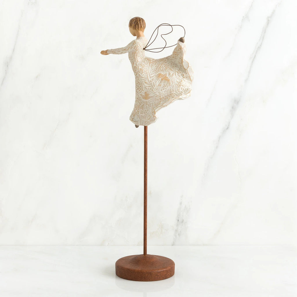 Brunette angel figurine in white dress on wooden stand with her arms out