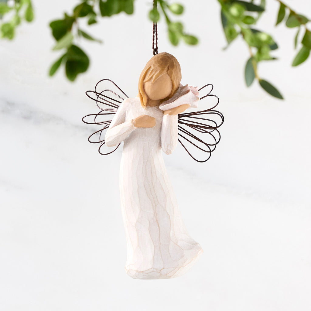Female angel with wire wings in cream dress, holding pink shell up to ear, ornament loop attached to head