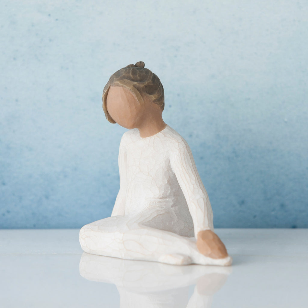 Small brunette girl figurine in white dress sitting down - blue background