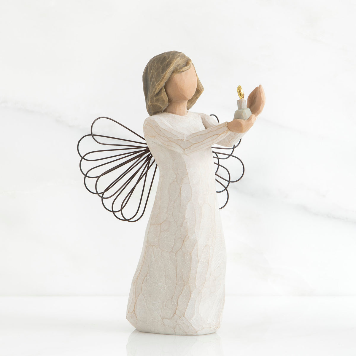 Faceless girl figurine wearing white dress holding up gold candle