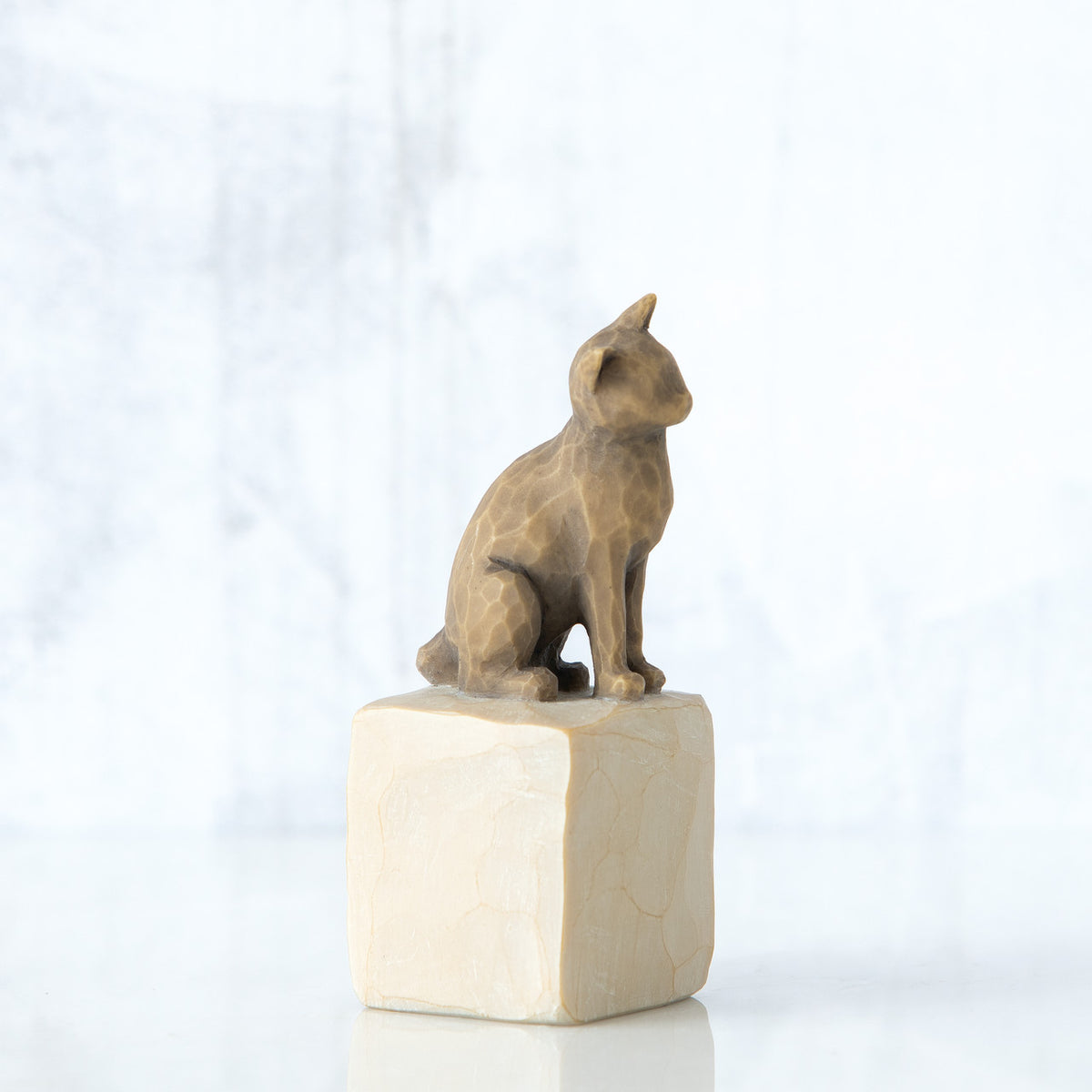 Dark brown cat figurine sitting on white rock