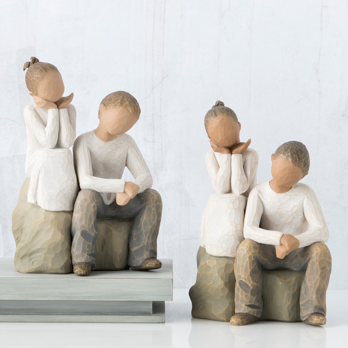 Set of two - girl and boy figurines in white sitting next to one another on rocks