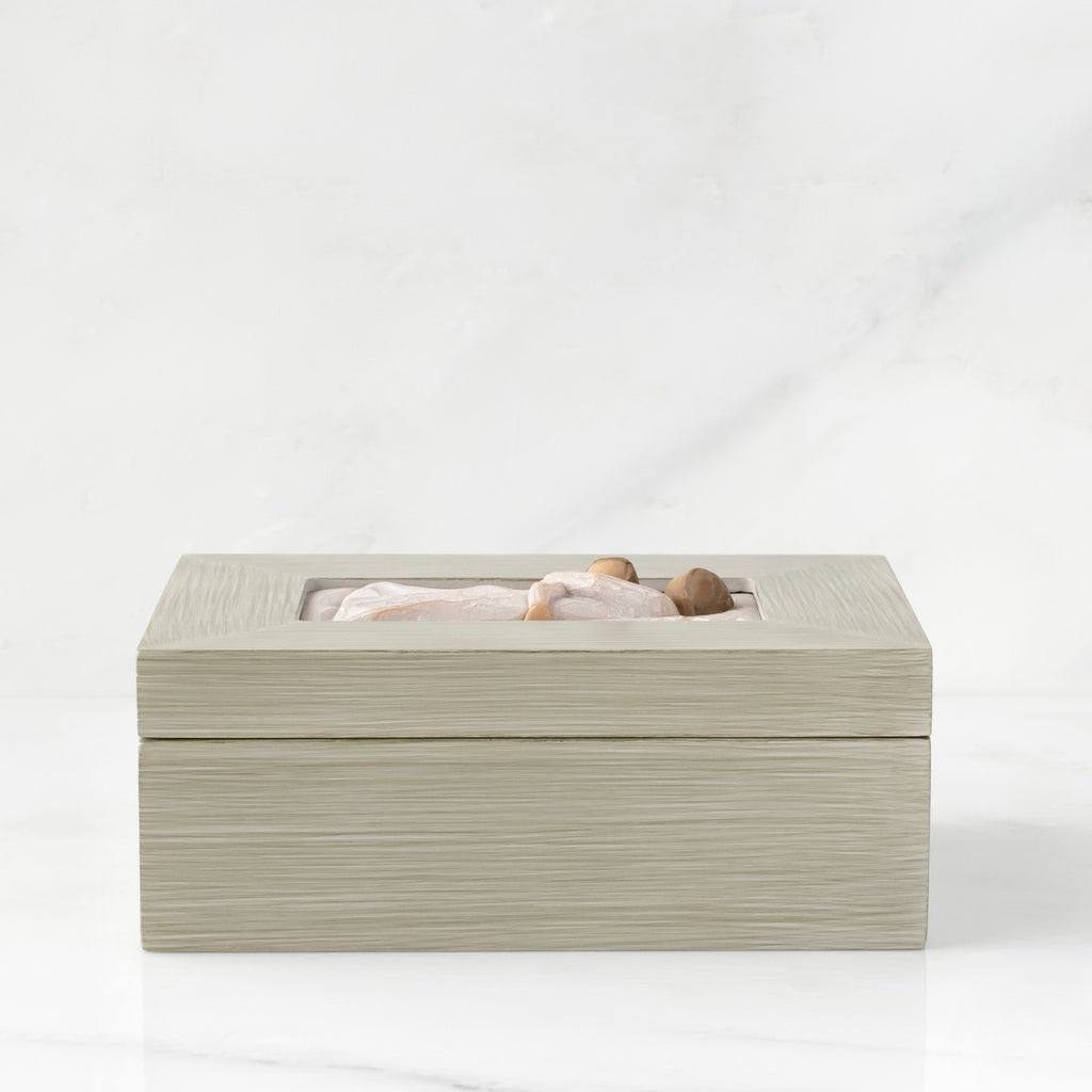 Side view: Light gray rectangular wood box with hinged lid, carving on lid of female and child embracing in cream dresses