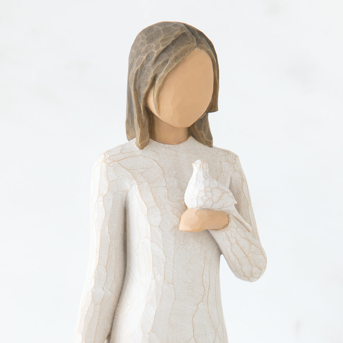 Close view of brunette girl figurine in white dress holding white dove