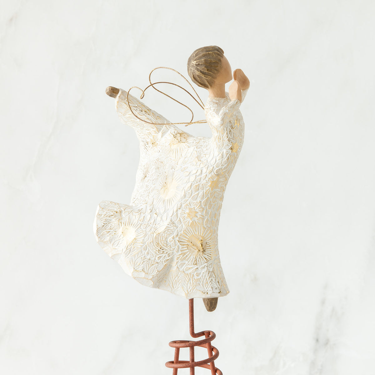 Side view of brunette angel figurine in white dress daning on red stand with arms to her face