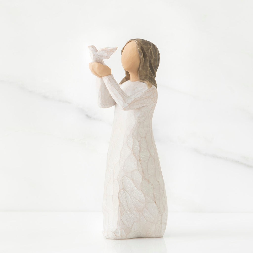 Faceless woman figurine in white dress holding up white bird in her arms