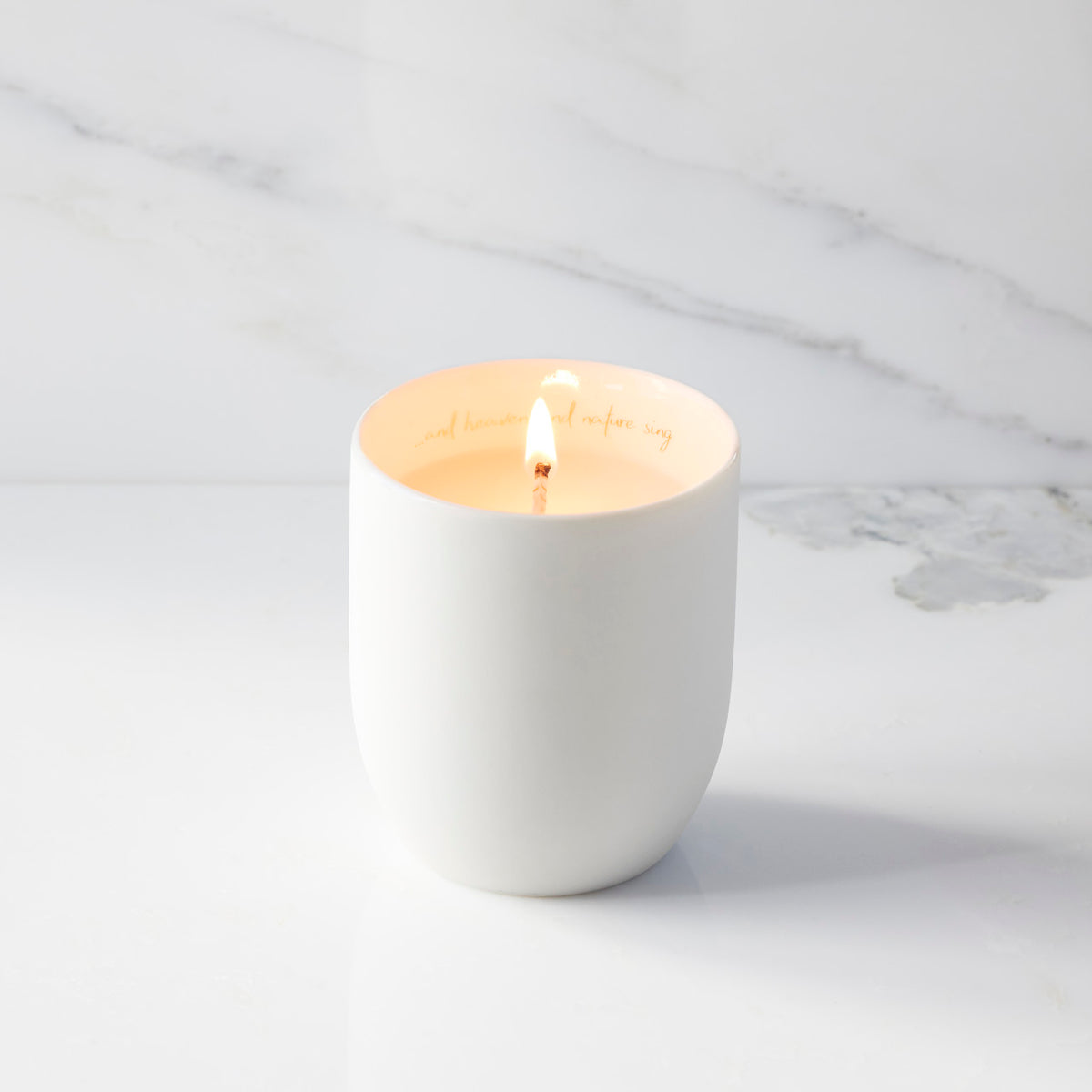 Lit filled scented candle with unglazed cream tapered cylinder vessel, sentiment written in gold inside rim, plant-based wax blend, all-cotton wick