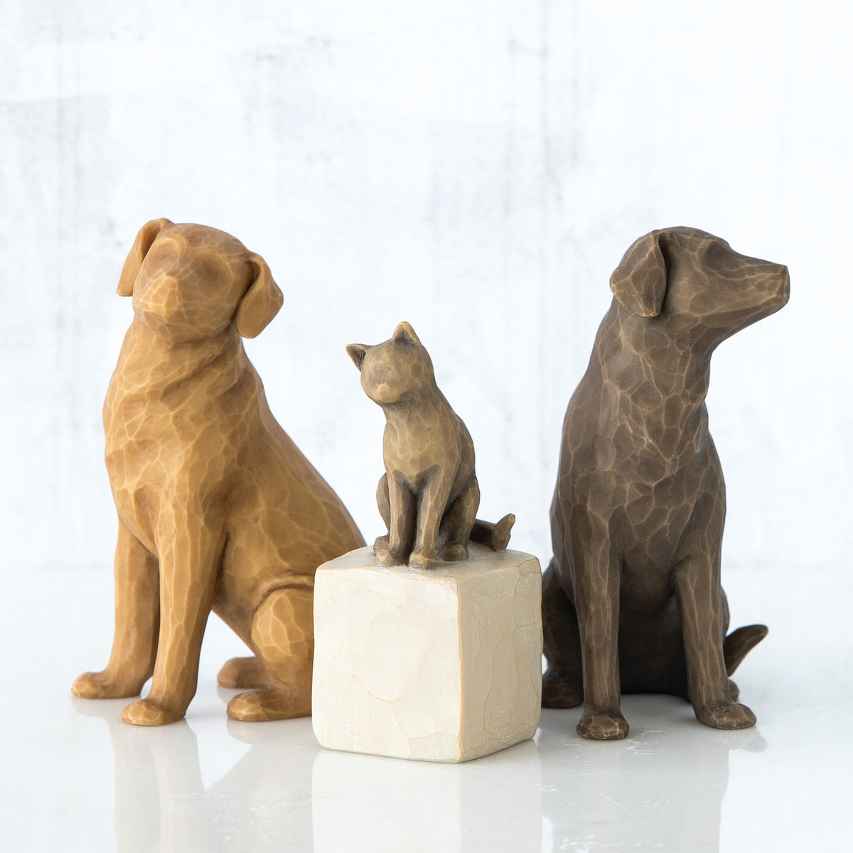 Two dog figurines in between cat sitting on white rock