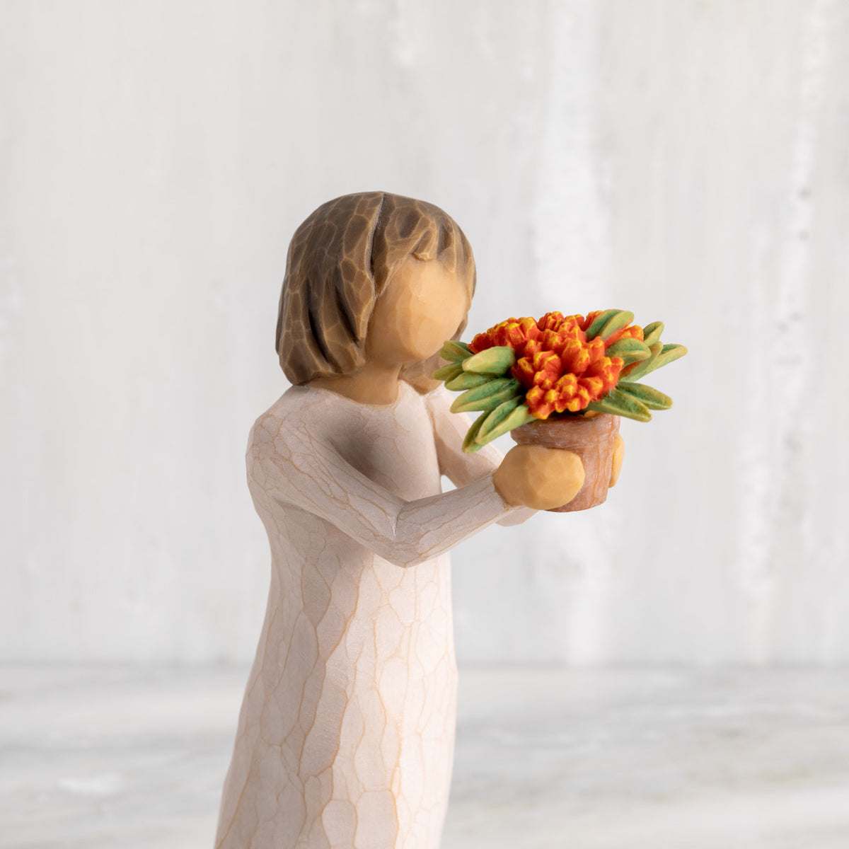 Detail: figure holding orange flowering milkweed plant in terracotta pot