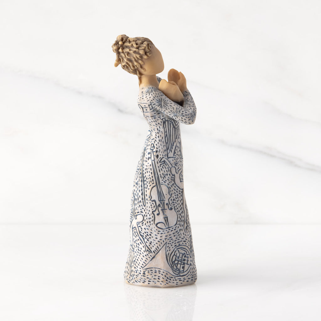 Facing right: Lighter-skin figure carved with contrasting pattern of dark blue musical symbols, instruments, dancing forms