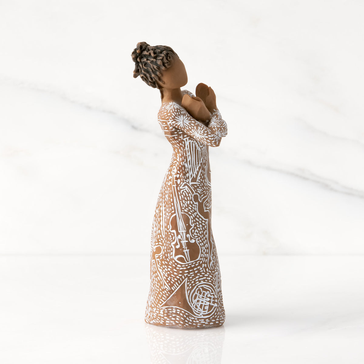 Facing right: Darker-skin figure carved with contrasting pattern of white musical symbols, instruments, dancing forms
