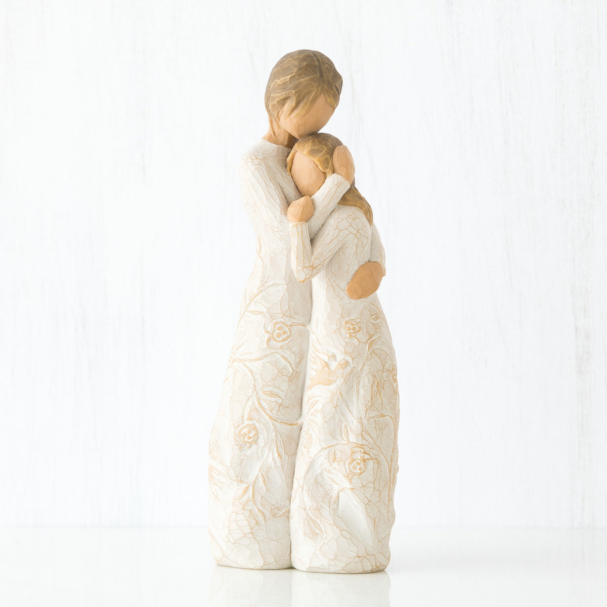 Mother faceless figurine hugging faceless daughter figurine - both standing wearing white dresses