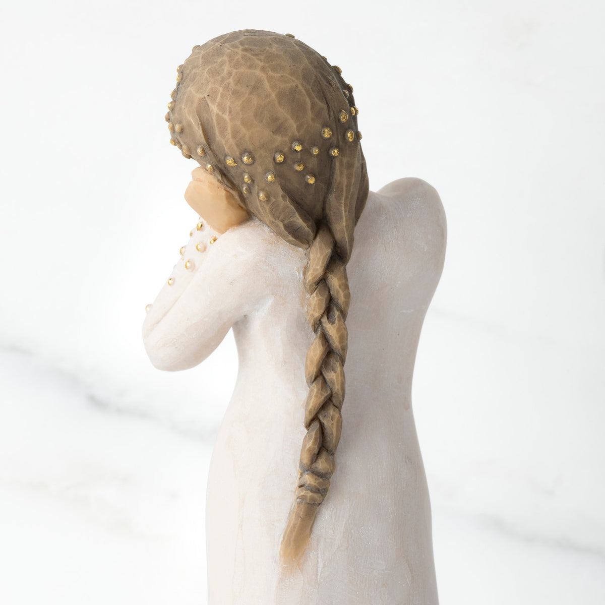 Cropped view of back of figure, showing braid with gold lead dot detail in hair