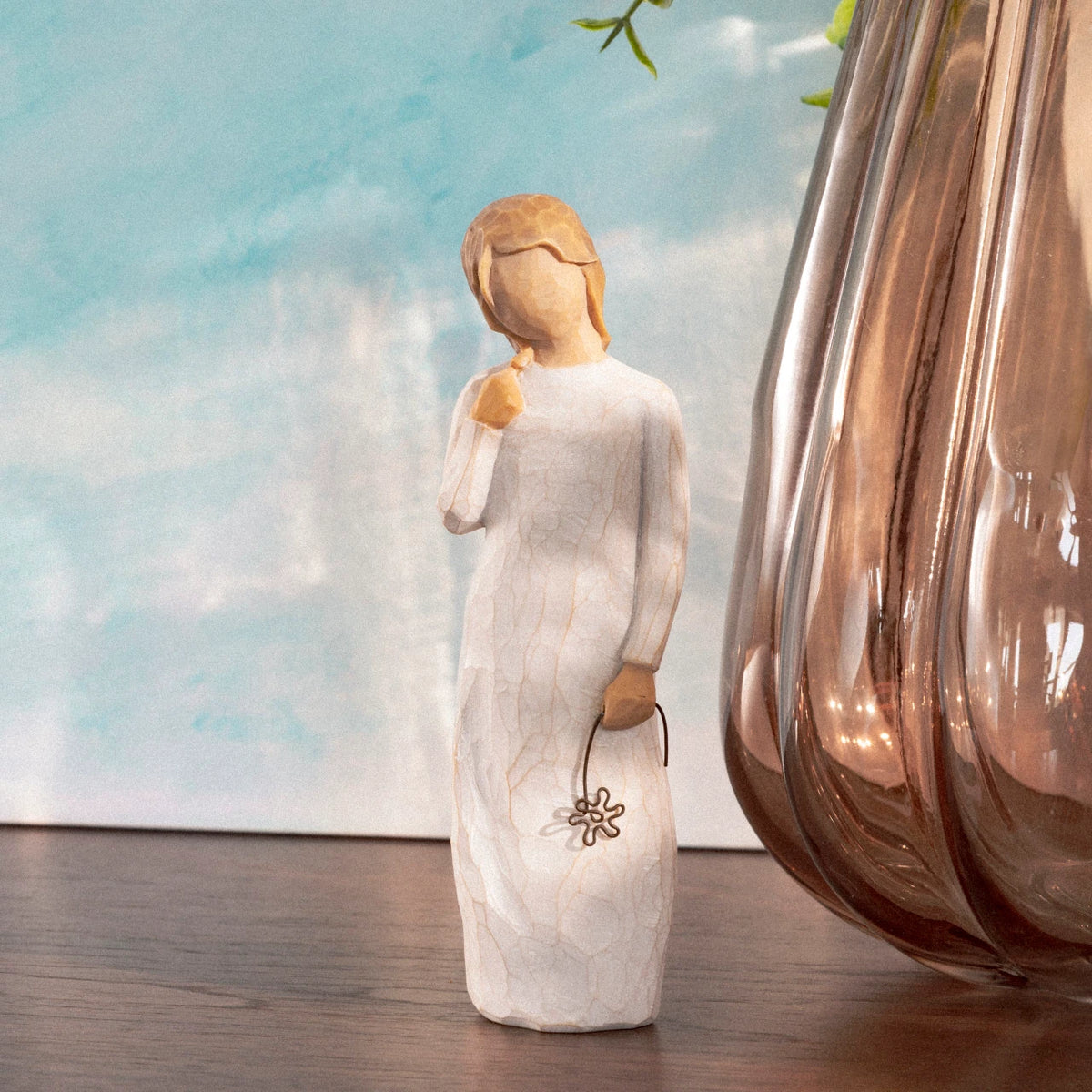 Willow Tree Remember, 5.5”h hand-painted standing resin figure in cream dress holding drooping wire flower in hand, on table with glass vase